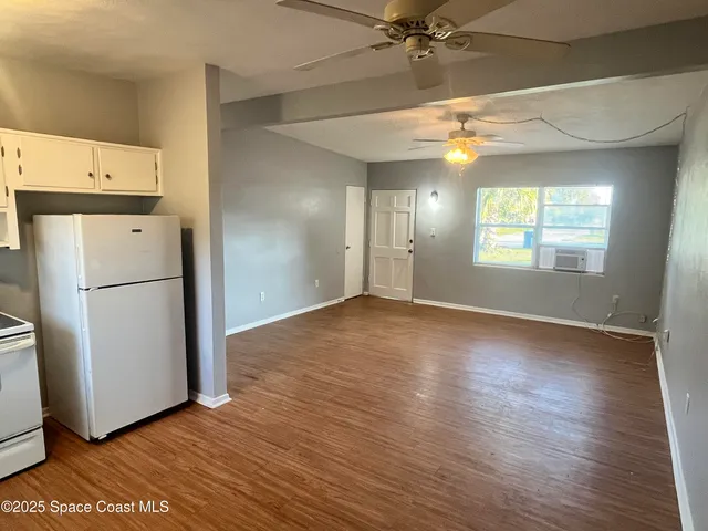 an empty room with wooden floor cabinet and windows