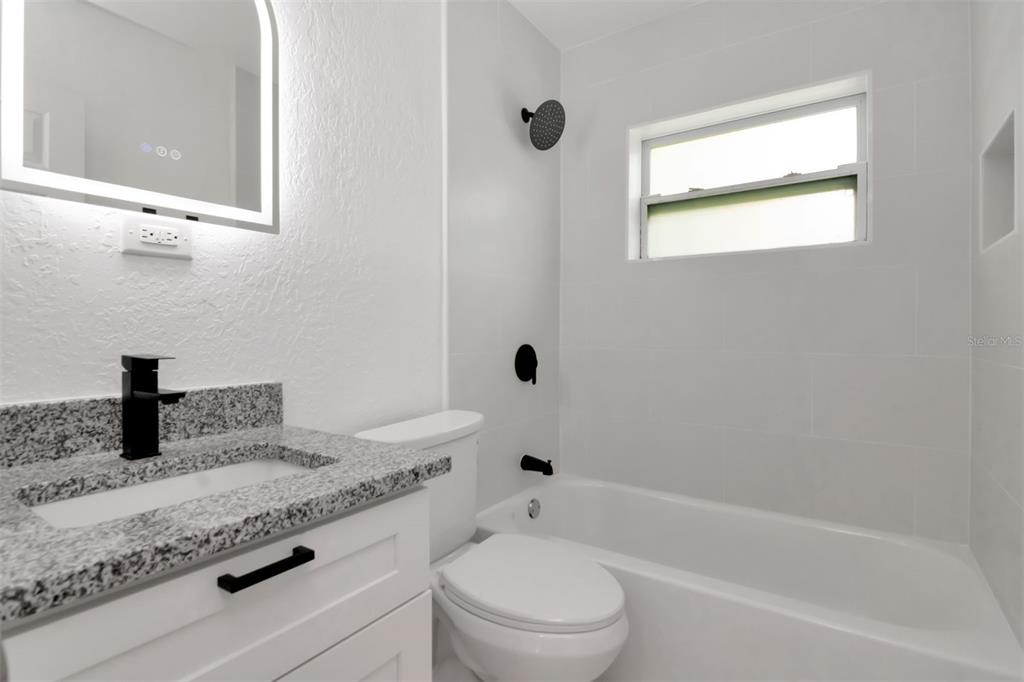7148 Ramor Lane New Port Richey, FL 34653 - Photo 18 of 26 a bathroom with a granite countertop toilet a sink and a bathtub