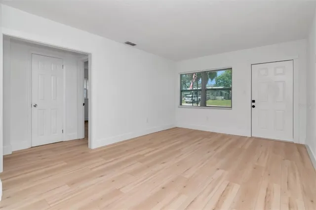 a view of an empty room with wooden floor and a window