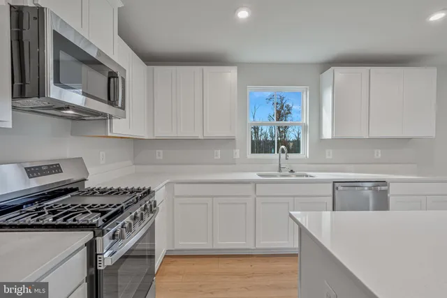 a kitchen with stainless steel appliances white cabinets and a stove top oven