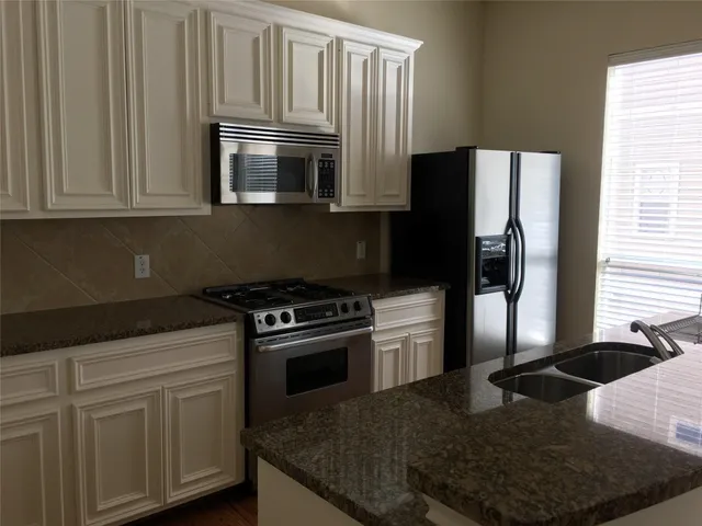 a kitchen with stainless steel appliances granite countertop a refrigerator stove and sink