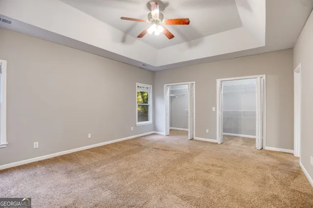 an empty room with closet and a chandelier fan