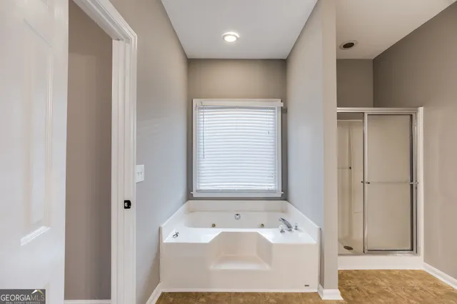 a bathroom with a tub a window and a rug