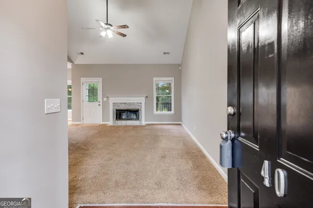 an empty room with windows fireplace and fan