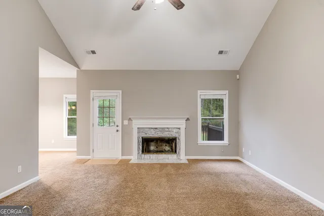an empty room with windows and fireplace
