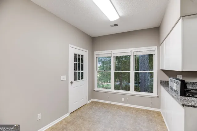 a view of an empty room with a window and cabinet