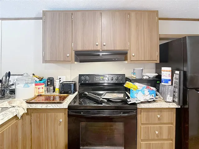 a kitchen with granite countertop a stove top oven a sink dishwasher and a refrigerator with wooden cabinets