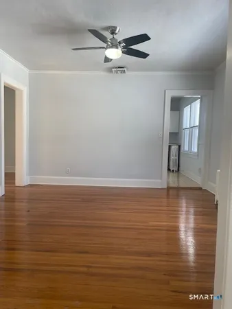 a view of a room with wooden floor and a ceiling fan