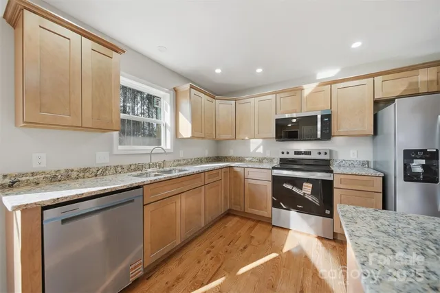 a kitchen with stainless steel appliances granite countertop a sink stove microwave and refrigerator