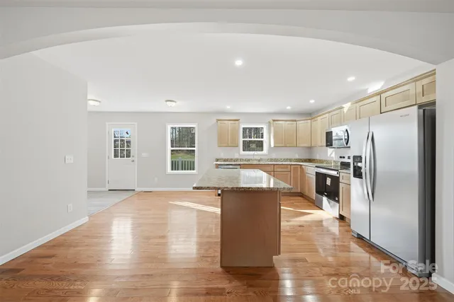 a large kitchen with kitchen island a large counter top stainless steel appliances and cabinets