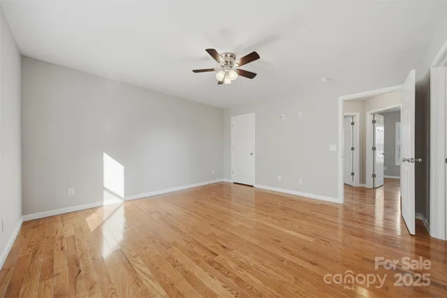 a view of empty room with wooden floor and ceiling fan