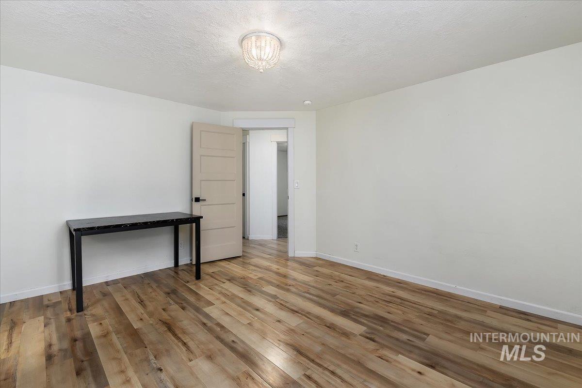 9215 West Preece Street Boise, ID 83704 - Photo 8 of 22 Spacious room featuring wood-finish flooring, crisp white walls, and a contemporary ceiling light fixture