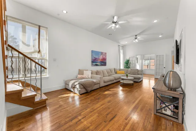 a living room with furniture hard wood floor and a large window