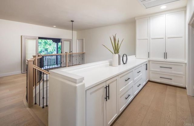a kitchen with white cabinets and window