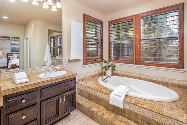 a bath tub sitting next to a bathroom sink and a granite counter space