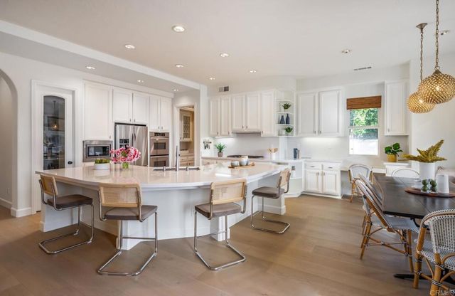 a living room with stainless steel appliances kitchen island granite countertop furniture and a wooden floor