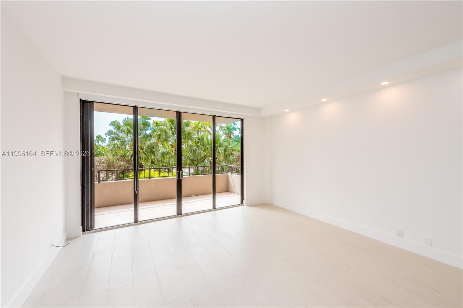 a view of an empty room with wooden floor and next to a window