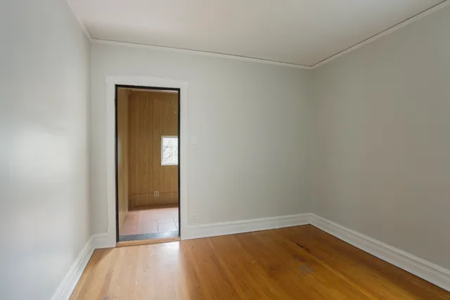a view of an empty room with wooden floor and closet