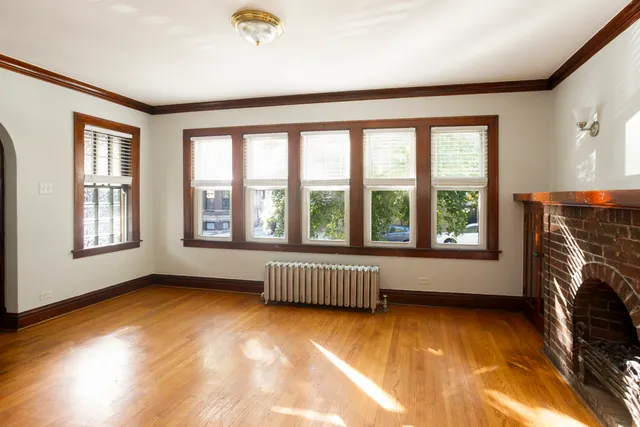 a view of an empty room with a fireplace and wooden floor