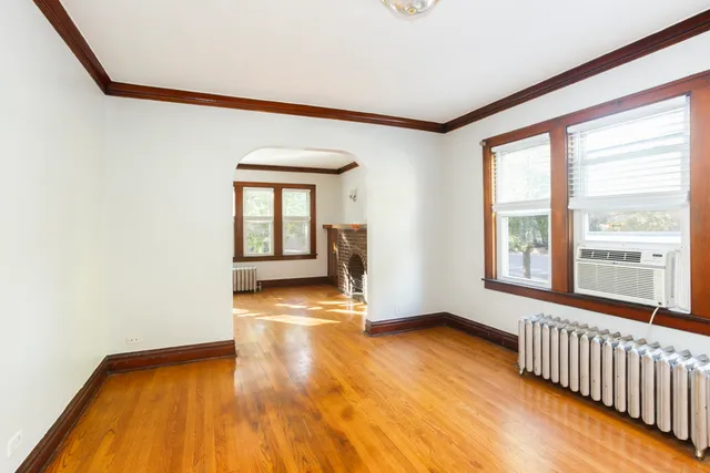 a view of an empty room with a window and wooden floor