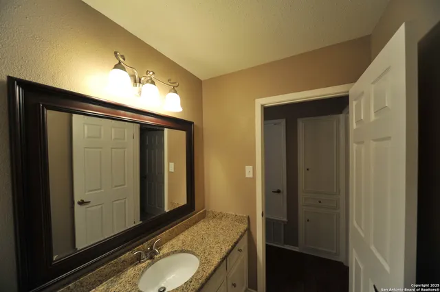 a bathroom with a granite countertop sink and a mirror