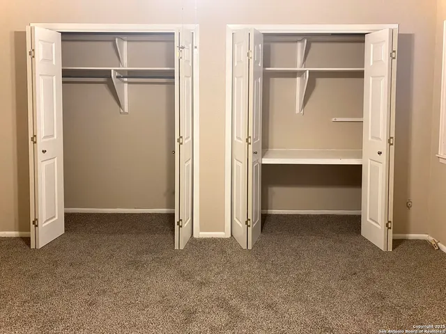 a view of an empty room with closet and a window