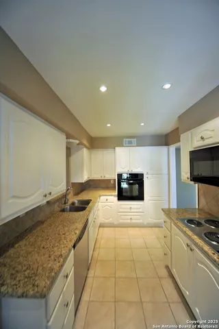 a large kitchen with stainless steel appliances granite countertop a sink and a stove