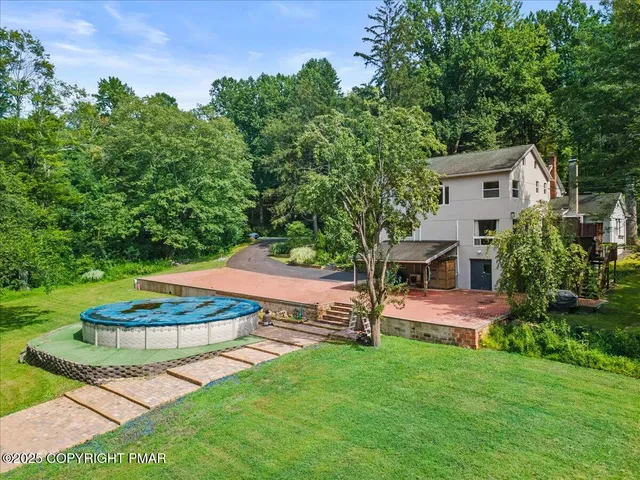an aerial view of residential house with outdoor space and trees all around