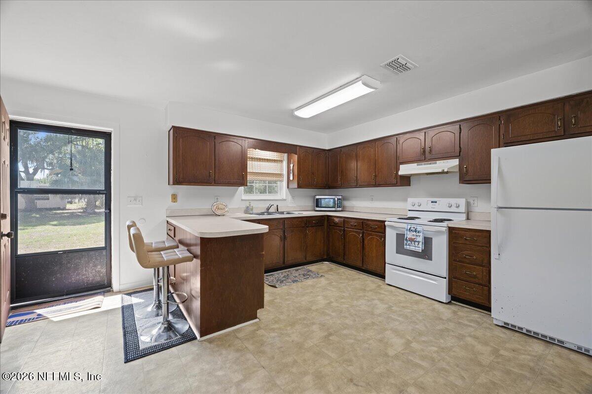 986 Highway 20 Interlachen, FL 32148 - Photo 16 of 53 a kitchen with stainless steel appliances kitchen island granite countertop a refrigerator stove top oven and sink