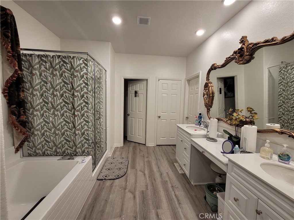 7561 Baerss Road Riverside, CA 92507 - Photo 19 of 27 a bathroom with a double vanity sink a mirror a bathtub and shower