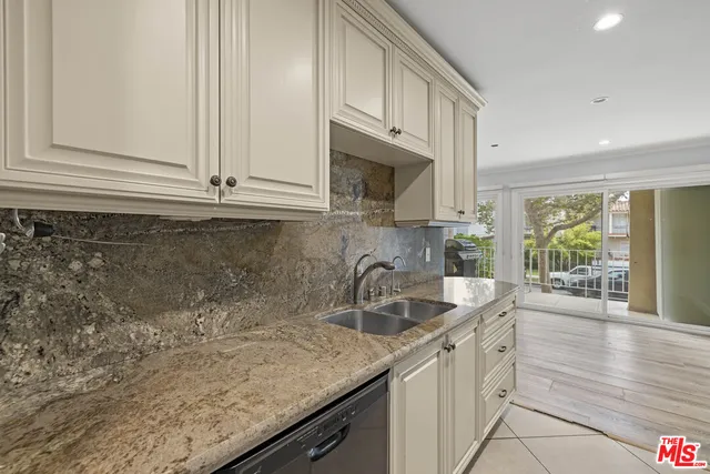 a kitchen with granite countertop a sink a stove and cabinets