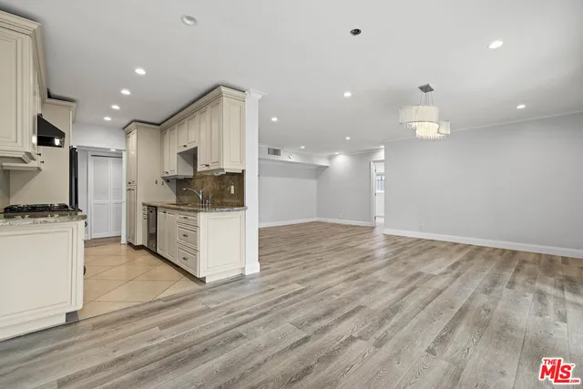 a view of kitchen with kitchen island wooden floor cabinets and stainless steel appliances