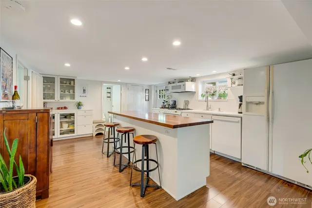 a kitchen with stainless steel appliances granite countertop a table chairs refrigerator and sink