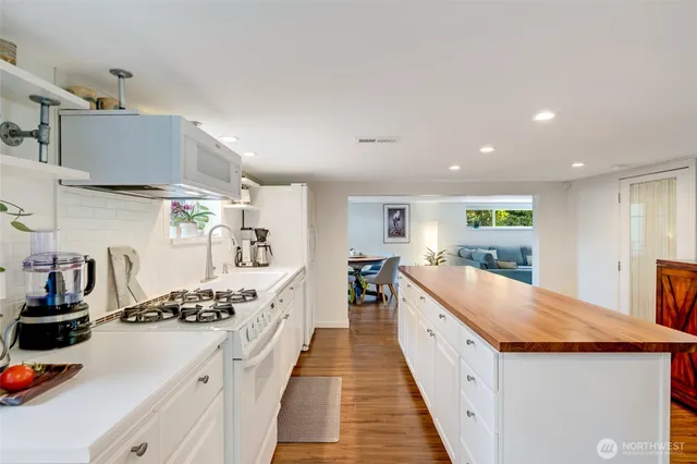 a large kitchen with stainless steel appliances a sink a counter top space and cabinets