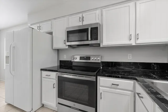 a kitchen with stainless steel appliances granite countertop white cabinets and a stove top oven