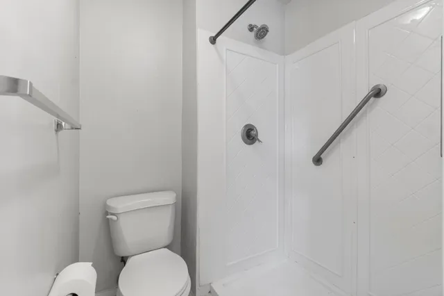 a white toilet sitting next to a shower
