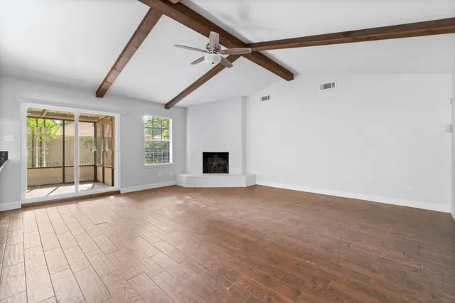 a view of an empty room with a window and wooden floor