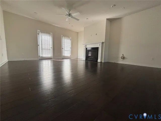 an empty room with wooden floor fireplace and windows
