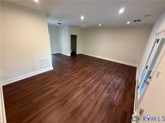 an empty room with wooden floor and entrance