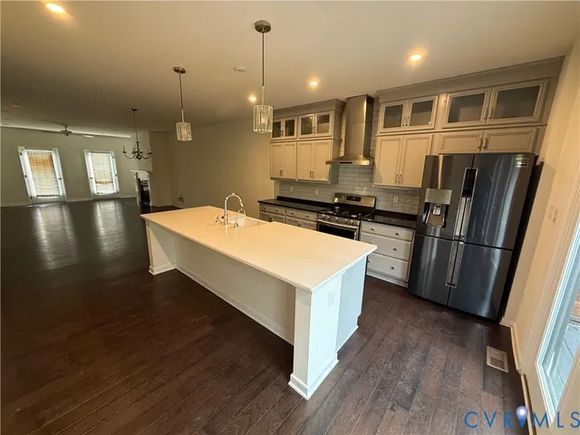 a kitchen with stainless steel appliances a stove a sink a refrigerator white cabinets and wooden floor