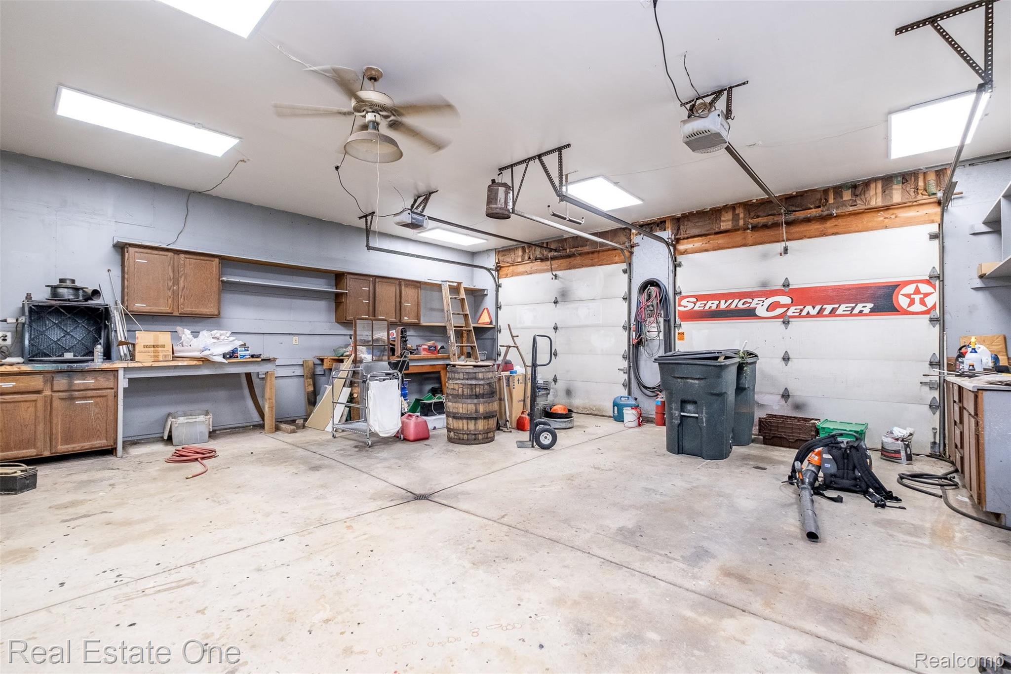 11030 Marshall Road South Lyon, MI 48178 - Photo 61 of 83 Concrete flooring, two automatic garage doors, built-in cabinetry, overhead lighting, and a ceiling fan