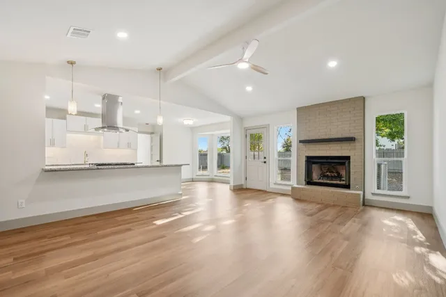 an empty room with wooden floor and a kitchen