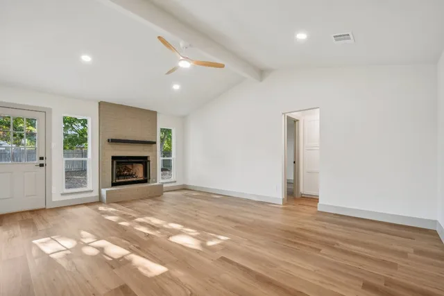 a view of empty room with wooden floor and fireplace