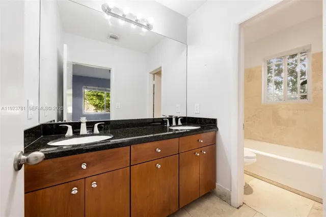a bathroom with a granite countertop double vanity sink a mirror and a bathtub