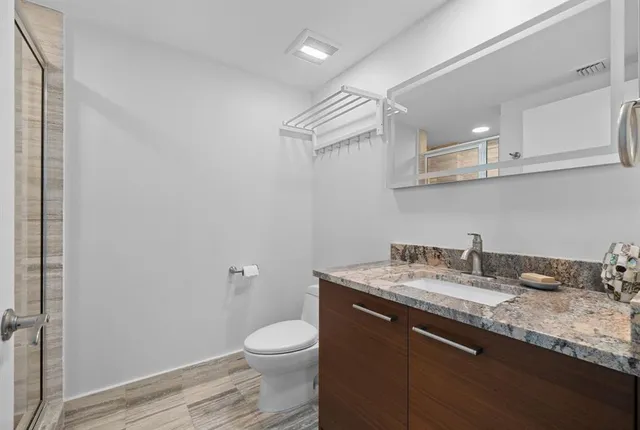 a bathroom with a granite countertop sink a toilet and a mirror