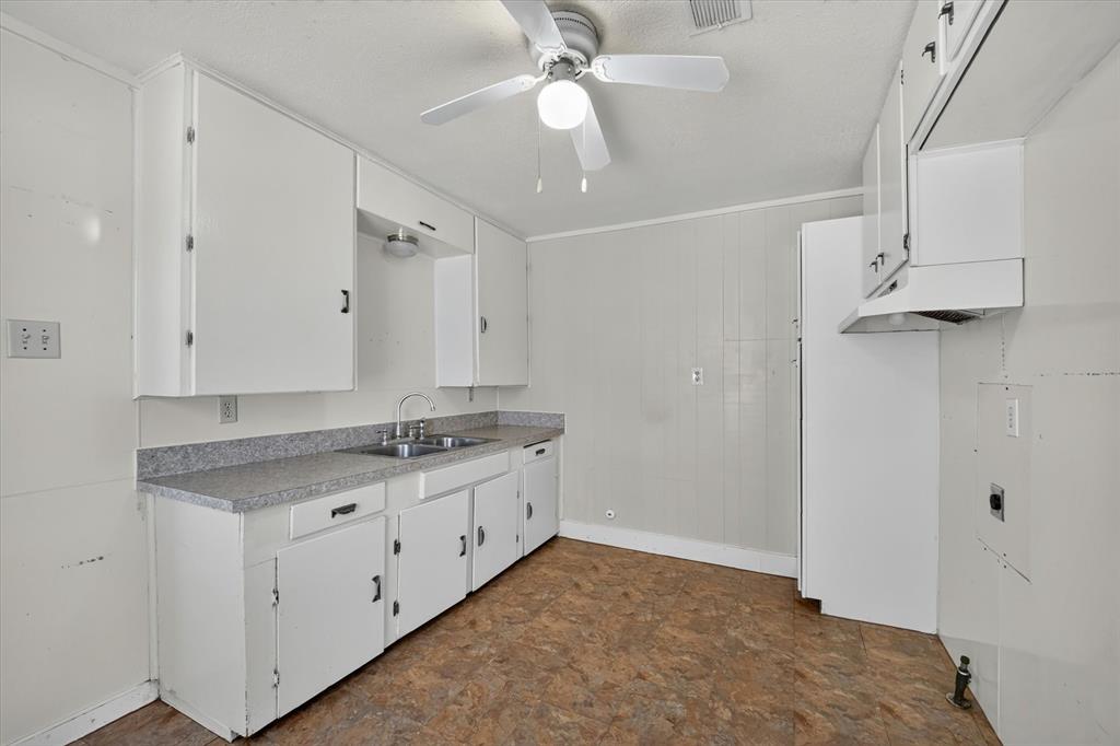 4450 Percy Street Lancaster, TX 75134 - Photo 8 of 18 Kitchen featuring white cabinetry, a dual basin stainless steel sink, a gray speckled countertop, and resilient flooring