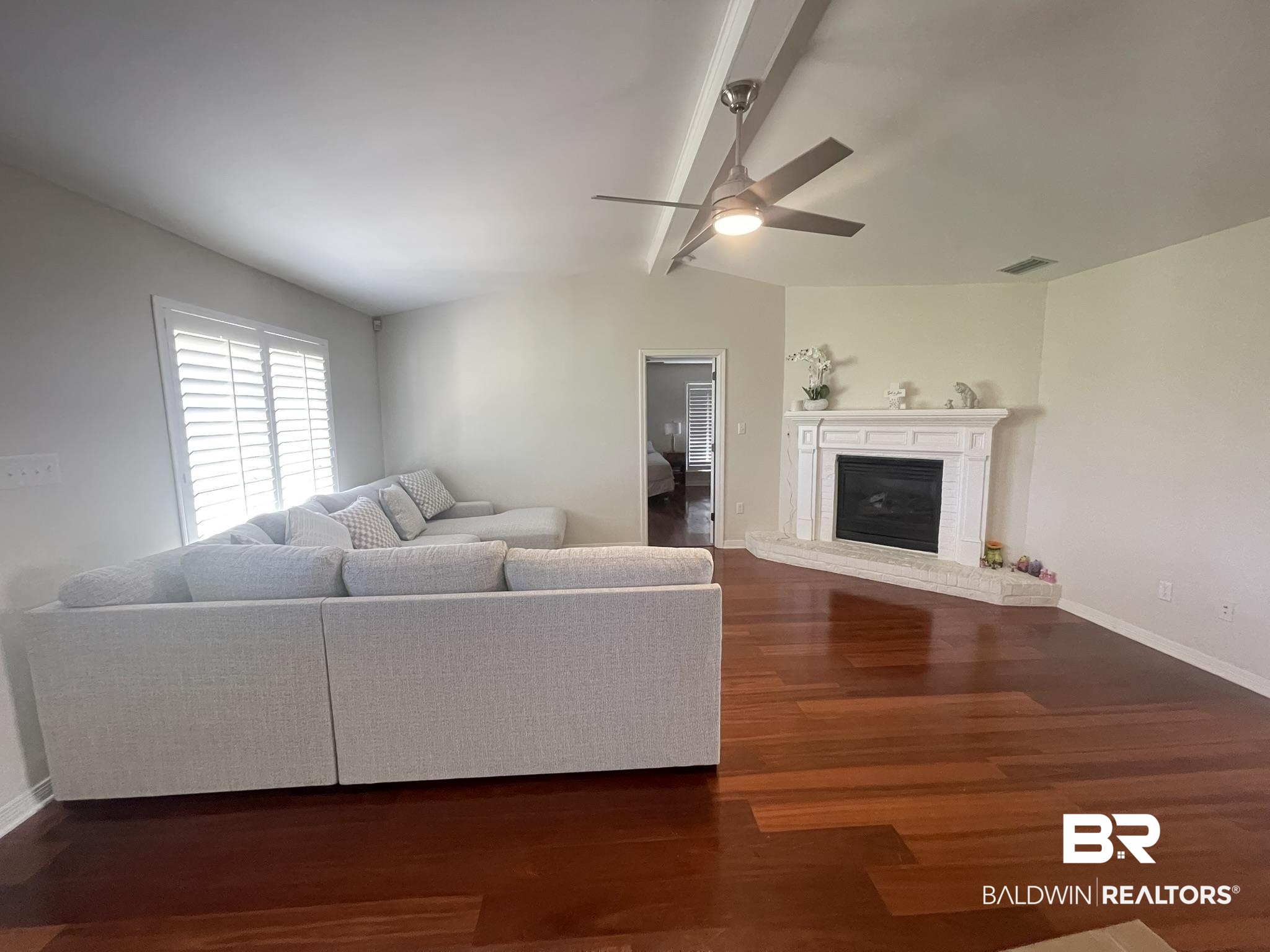 35405 Pine Road South Stapleton, AL 36578 - Photo 3 of 29 Living area featuring ceiling fan, dark wood-type flooring, a brick fireplace, and vaulted ceiling with beams