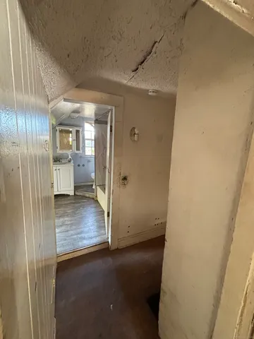 a view of a hallway to a room with wooden floor and cabinet