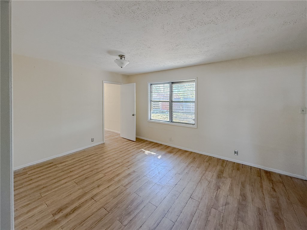 833 Booty Street Sinton, TX 78387 - Photo 3 of 9 an empty room with wooden floor and windows