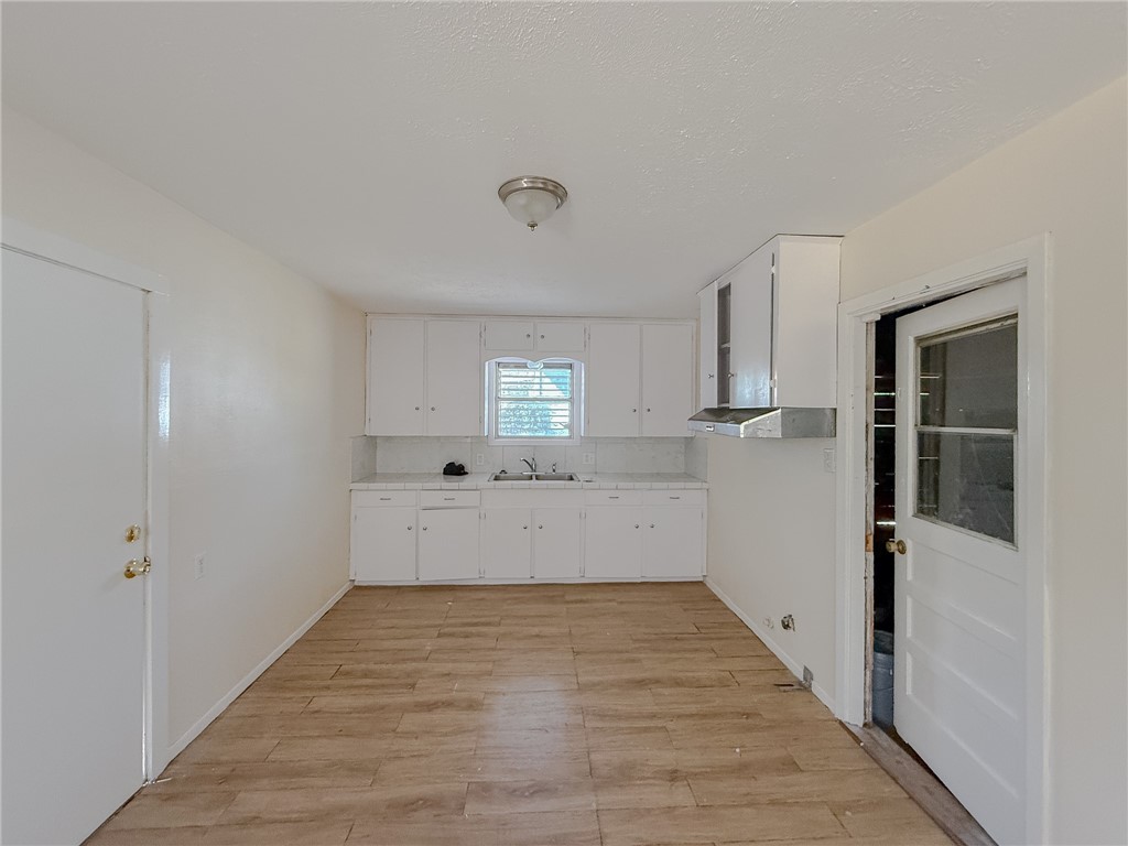 833 Booty Street Sinton, TX 78387 - Photo 4 of 9 a view of a kitchen with wooden floor and electronic appliances
